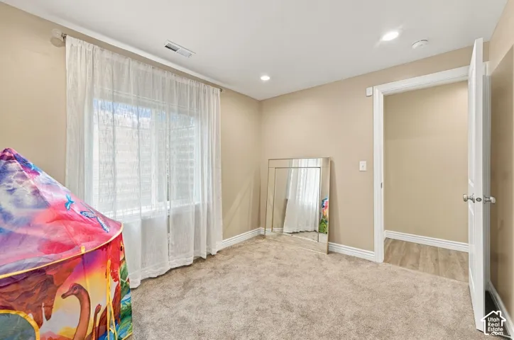 Neutral wall tones, recessed lighting, carpeted flooring, and a sliding window with clean-lined interior trim