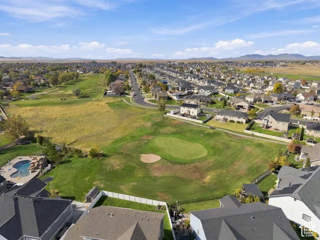 Aerial perspective of a property featuring an in-ground swimming pool with rock-waterfall element, a private yard enclosed by vinyl fencing, and direct access to an expansive open green space
