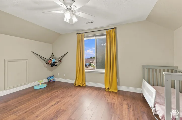 Room featuring wood-finish flooring, a ceiling fan with light fixture, and an access panel