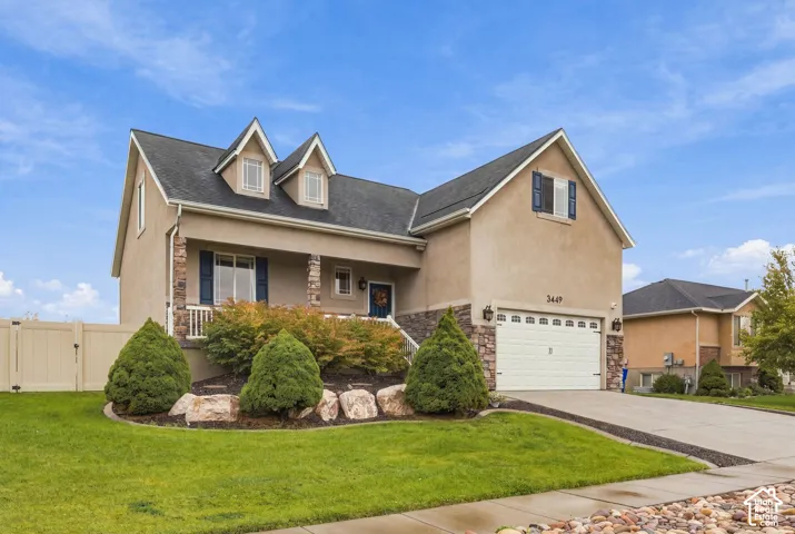 Multi-level exterior featuring stone veneer accents, dual roof dormers, a covered front porch, and an attached two-car garage