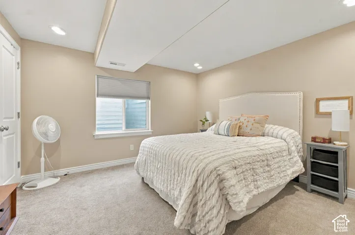 Neutral-toned interior featuring recessed ceiling lighting, wall-to-wall carpeting, and a window with a fitted roller shade