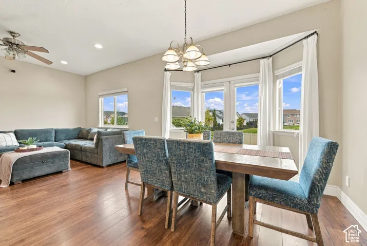 Open-concept interior featuring wood-finish flooring, a bay window, glass-panel patio doors, recessed lighting, and a multi-arm chandelier