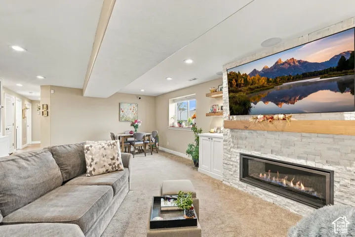 Stacked stone fireplace with a linear firebox and wood mantle, recessed lighting, and built-in cabinetry with floating shelving