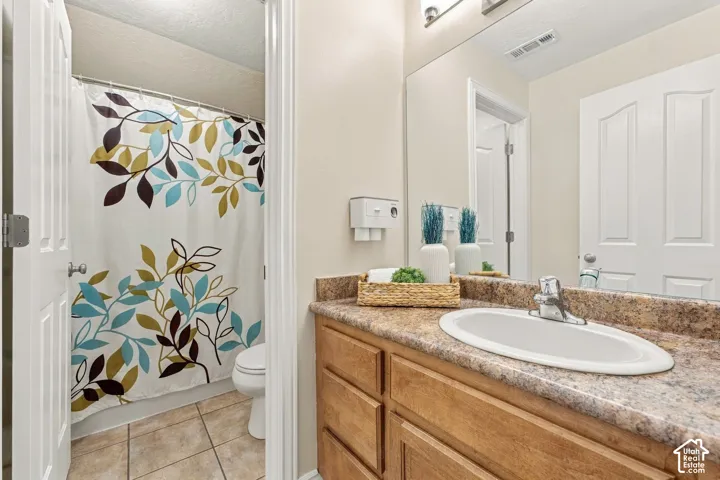 Bathroom featuring a vanity with wood cabinetry, a stone-finish countertop, an integrated oval sink, and a large wall-mounted mirror