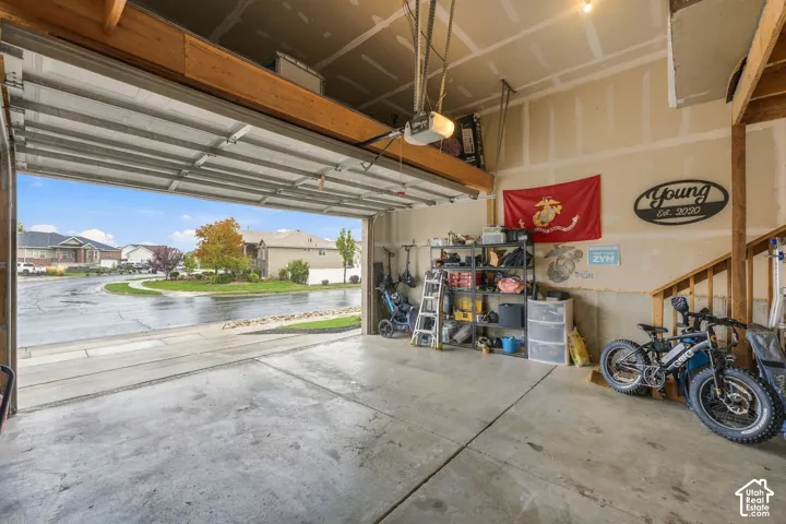 Multi-car garage featuring a concrete floor, an overhead garage door opener, and wooden staircase structure