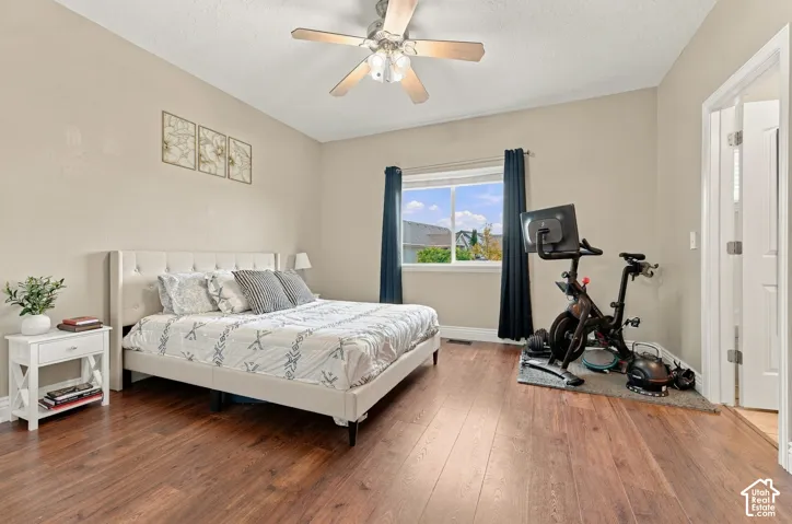 Room featuring wood-finish flooring, a neutral color palette, ceiling fan with integrated lighting, and a window with a horizontal sliding sash