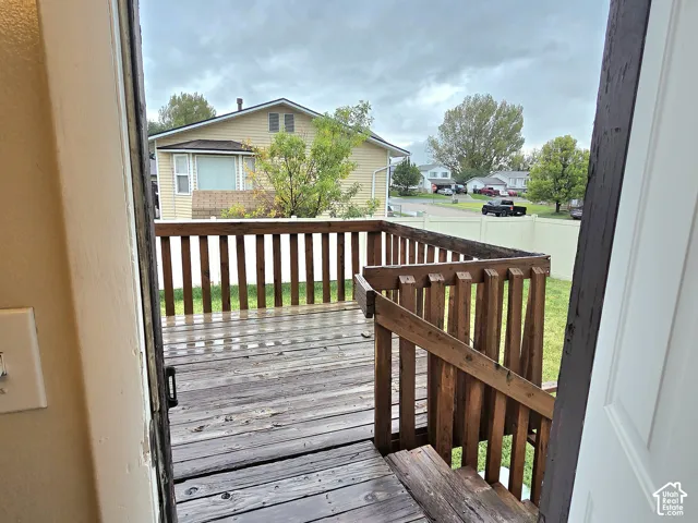 Elevated wood deck featuring vertical balusters, a staircase, and a surrounding vinyl privacy fence