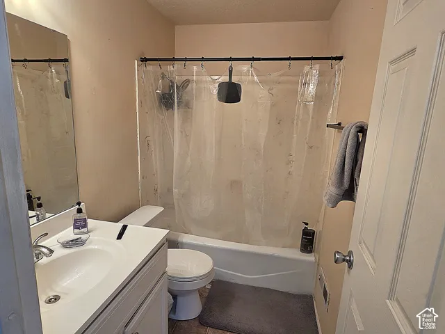 Bathroom featuring a white vanity cabinet, integrated sink with chrome faucet, wall-mounted mirror, and a combination tub and shower surround