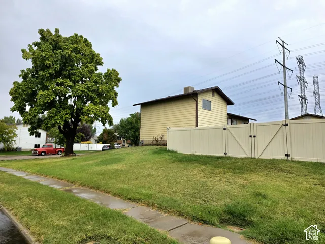 Corner lot featuring horizontal siding, a vinyl privacy fence, and a mature deciduous tree