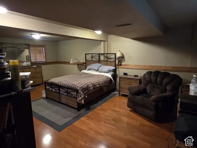 Wood-finish flooring, natural wood chair rail molding, recessed ceiling lighting, and a window with wood-slat blinds