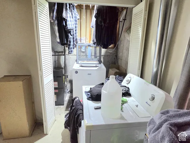Laundry area featuring louvered bifold doors and exposed structural masonry wall