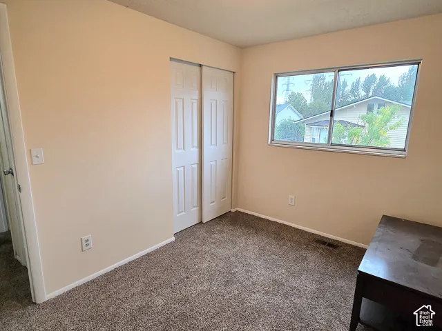 Neutral-toned interior featuring wall-to-wall carpeting, a dual-panel sliding closet door, and a horizontal sliding window