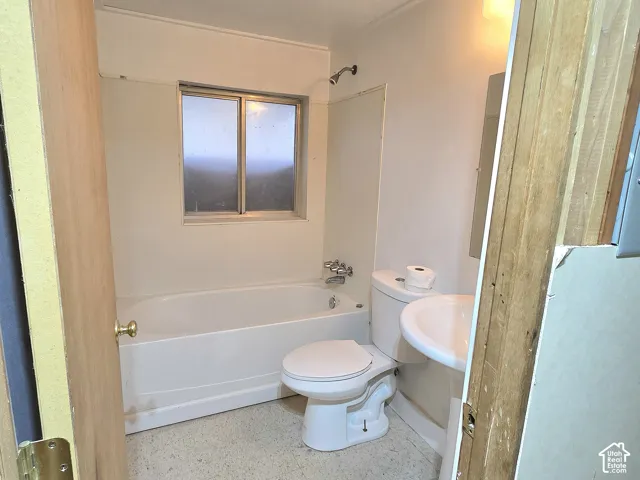 Bathroom featuring a white pedestal sink, porcelain toilet, bathtub-shower combination with integrated surround, and a single-pane sliding window