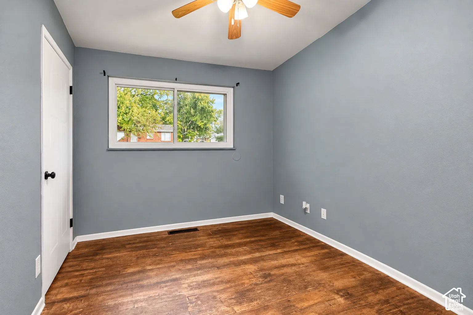Room featuring wood-finish flooring, sliding window, and ceiling-mounted light fixture with fan