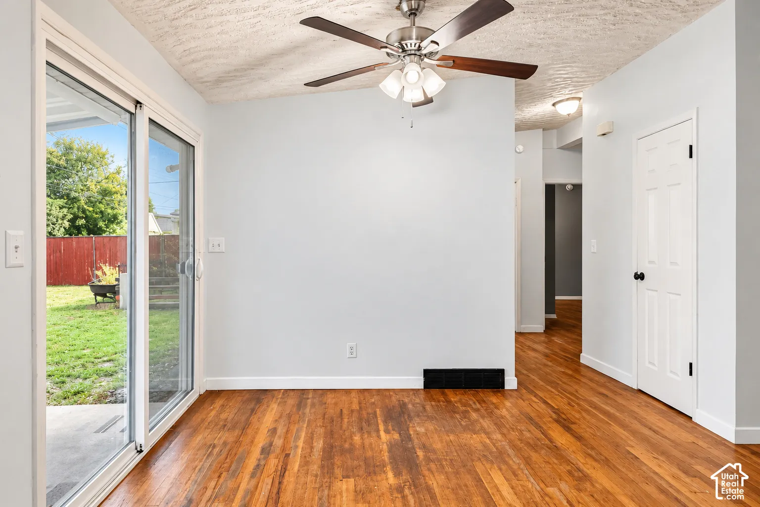 Interior featuring wood-finish flooring, sliding glass door, ceiling fan with integrated lighting, and six-panel interior door