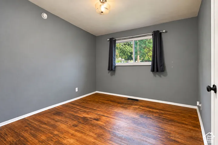 Room featuring wood-finish flooring, neutral-toned walls, a sliding window, and a central ceiling light fixture