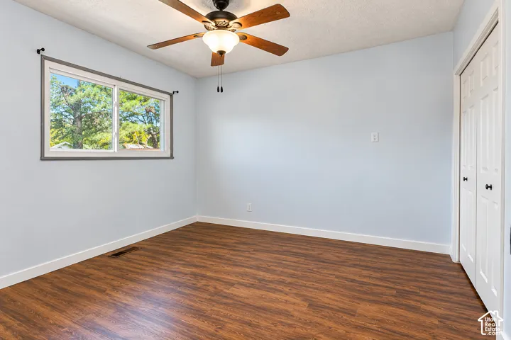 Room featuring wood-finish flooring, a horizontal sliding window, a ceiling fan with integrated lighting, and dual-panel closet doors