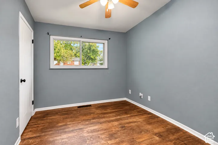 Room featuring wood-finish flooring, sliding window, and ceiling-mounted light fixture with fan