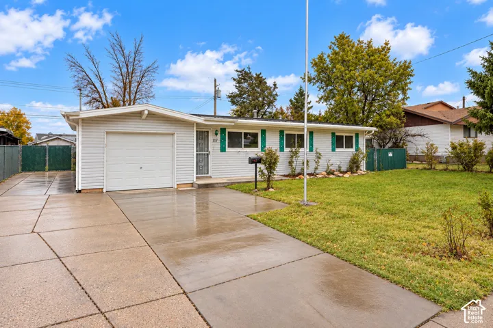 Single-story residence with horizontal siding, attached garage, concrete driveway, and front lawn