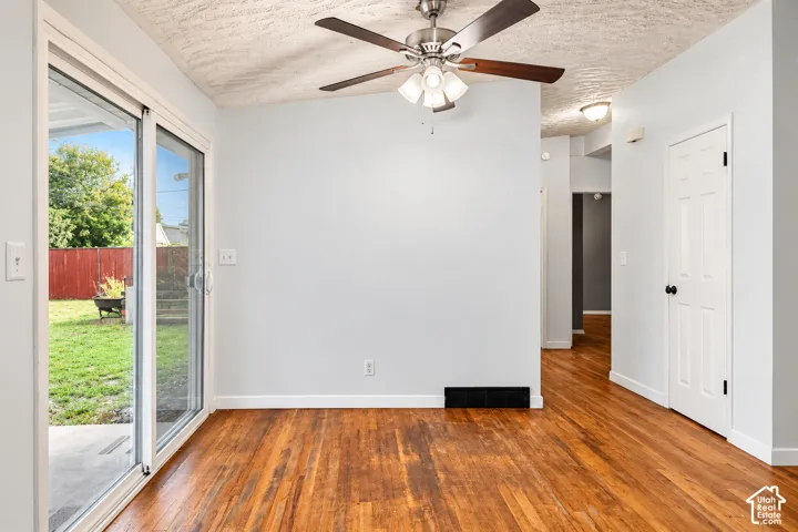 Interior featuring wood-finish flooring, sliding glass door, ceiling fan with integrated lighting, and six-panel interior door