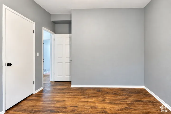 Interior space featuring grey-toned walls, wood-finish flooring, and white paneled interior doors with matte black hardware