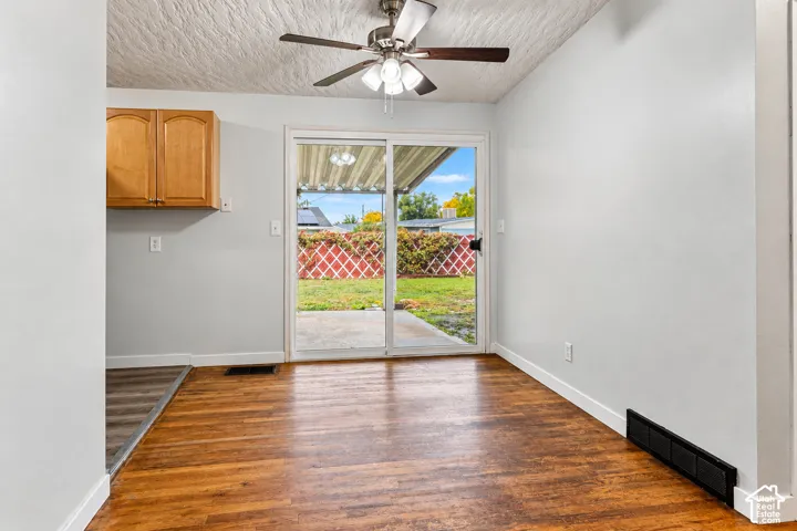 Wood-finish flooring, sliding glass door, ceiling fan with integrated lighting, and wooden cabinetry