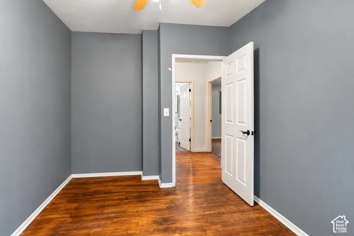 Room featuring wood-finish flooring, six-panel door with matte black hardware, and ceiling fan