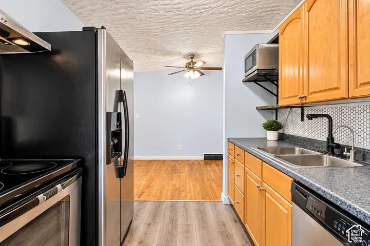 Kitchen featuring natural wood cabinetry, stainless steel appliances, a honeycomb tile backsplash, solid-surface countertops, and wood-finish flooring