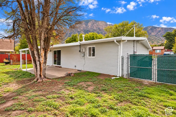 Exterior featuring horizontal siding, a concrete patio, mountain backdrop, and chain-link fencing
