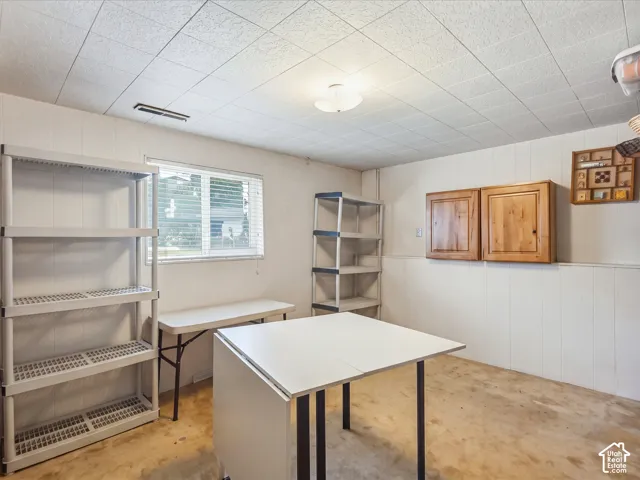 Textured ceiling panels, horizontal window with integrated blinds, and wall-mounted wooden cabinetry