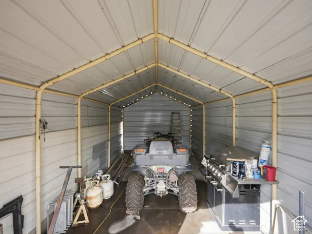 Enclosed metal carport featuring a peaked roof design and concrete flooring