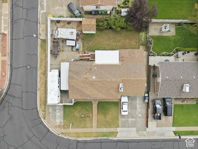 Corner lot property featuring a fenced backyard, concrete driveway, and a paved walkway leading to the entrance