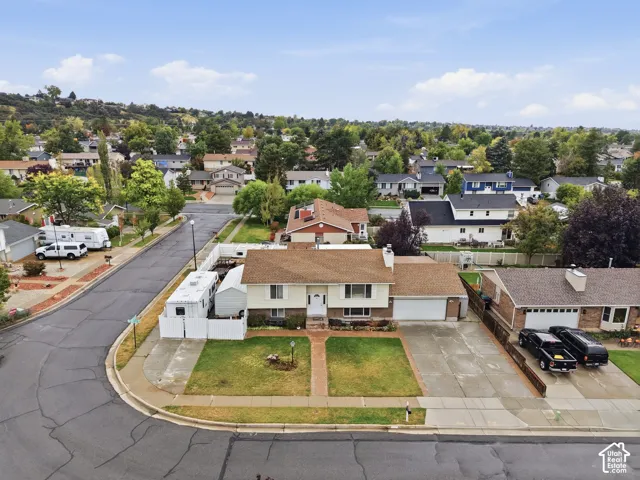 Split-level residence featuring a brick and horizontal siding exterior, attached two-car garage, shingled roof, and a paved driveway situated on a corner lot
