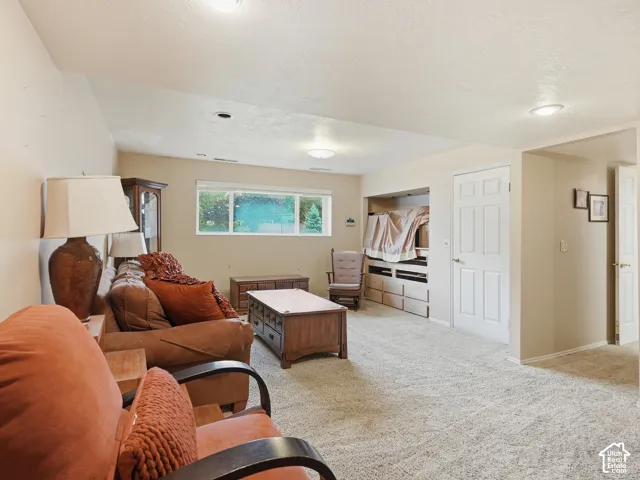 Living area featuring neutral wall tones, wall-to-wall carpeting, recessed ceiling lighting, and built-in shelving