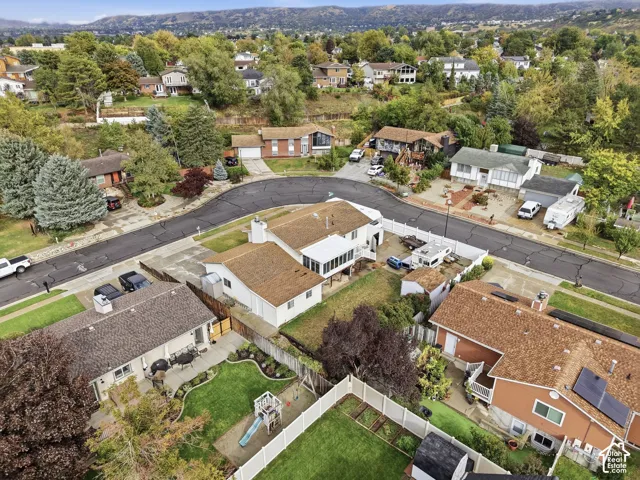 Aerial perspective featuring residential lots, paved cul-de-sac, white vinyl fencing, and mountain backdrop