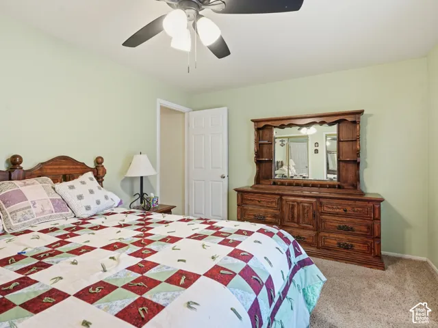 Neutral-toned carpeting, ceiling fan with integrated light fixture, and six-panel interior door