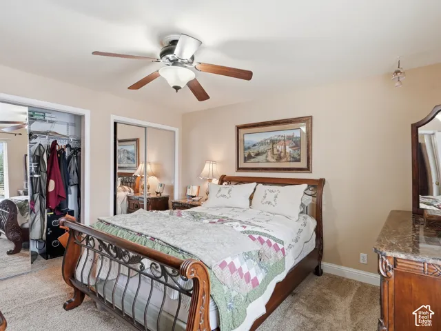 Bedroom featuring neutral wall paint, wall-to-wall carpeting, a multi-blade ceiling fan with integrated lighting, and mirrored closet doors