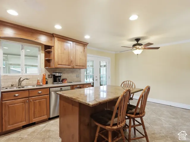 Kitchen featuring wood cabinetry, stone-surface island, ceramic tile flooring, recessed lighting, and a dual-basin stainless steel sink