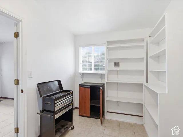 Room featuring white built-in shelving, tile flooring, and a window with a grid pattern