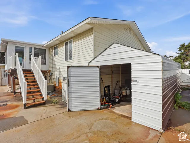 Exterior featuring a detached metal carport, elevated deck with stairs, and lap siding