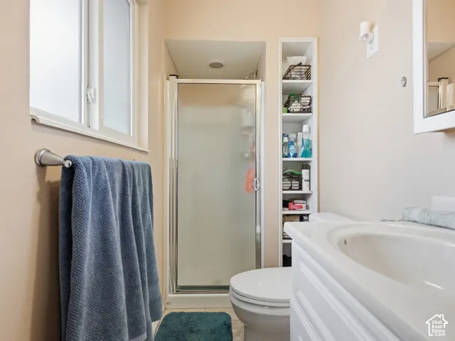 Bathroom featuring a shower stall with a framed glass door, built-in shelving, white vanity with an integrated basin, and window with natural light