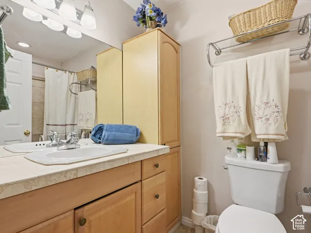 Bathroom featuring a light-wood vanity with an integrated countertop and sink, tall built-in cabinetry, an expansive wall-mounted mirror, and a multi-light fixture