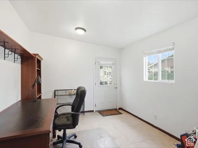 Neutral-toned tile flooring, built-in wooden shelving unit, exterior door with integrated glass pane, and a single-hung window with blinds
