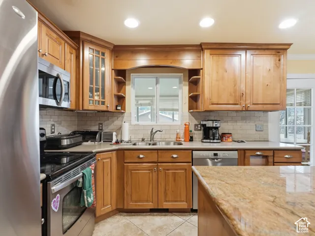 Kitchen featuring raised-panel wood cabinetry, natural stone countertops, stainless steel appliances, subway tile backsplash, and recessed lighting