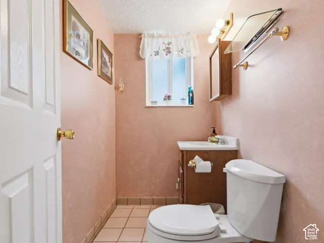 Bathroom featuring a single-sink wood vanity, light-toned ceramic tile flooring, a wall-mounted medicine cabinet, and a multi-bulb vanity light fixture