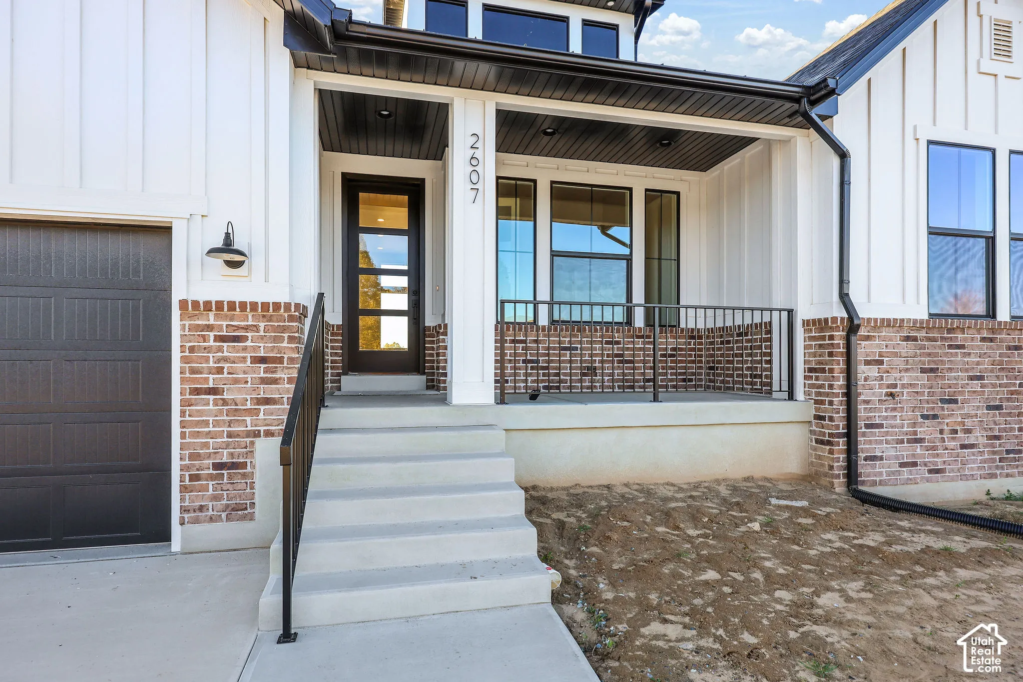 Modern farmhouse exterior featuring board and batten siding, a brick facade, and a covered porch