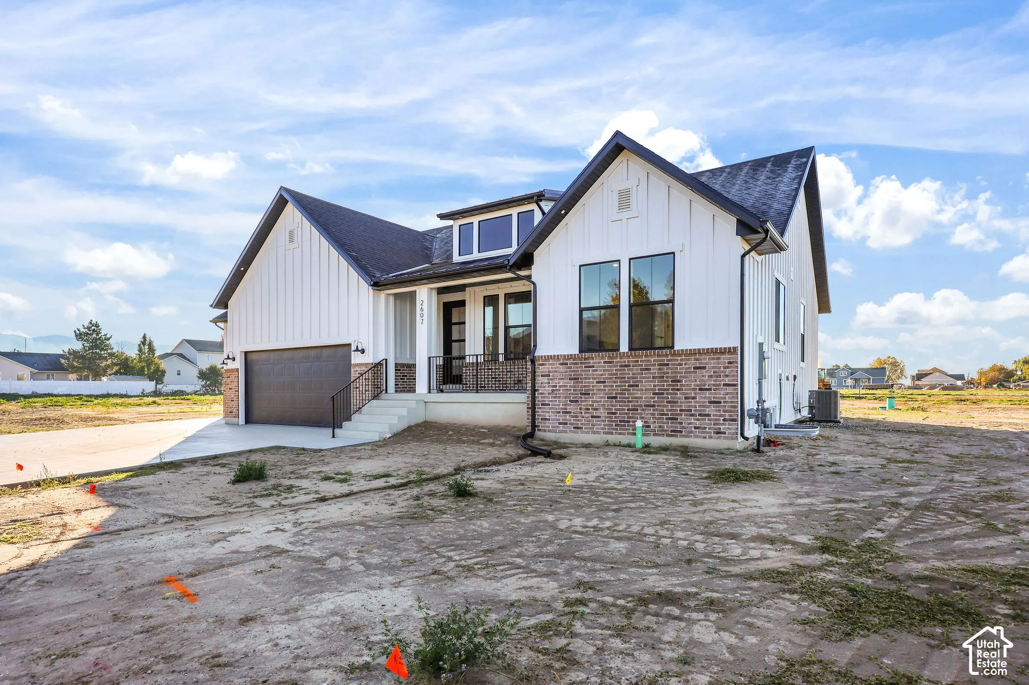 Modern farmhouse-style exterior featuring white board and batten siding, dark brick accents, a dark shingle roof, and black-framed windows