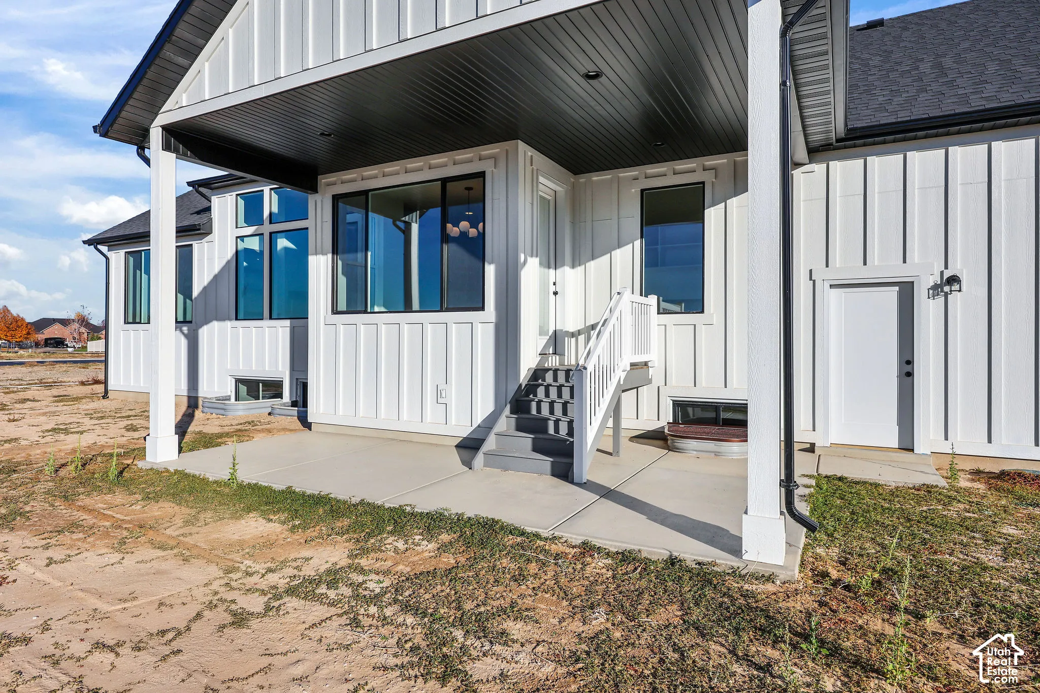 Covered concrete patio with white board and batten siding