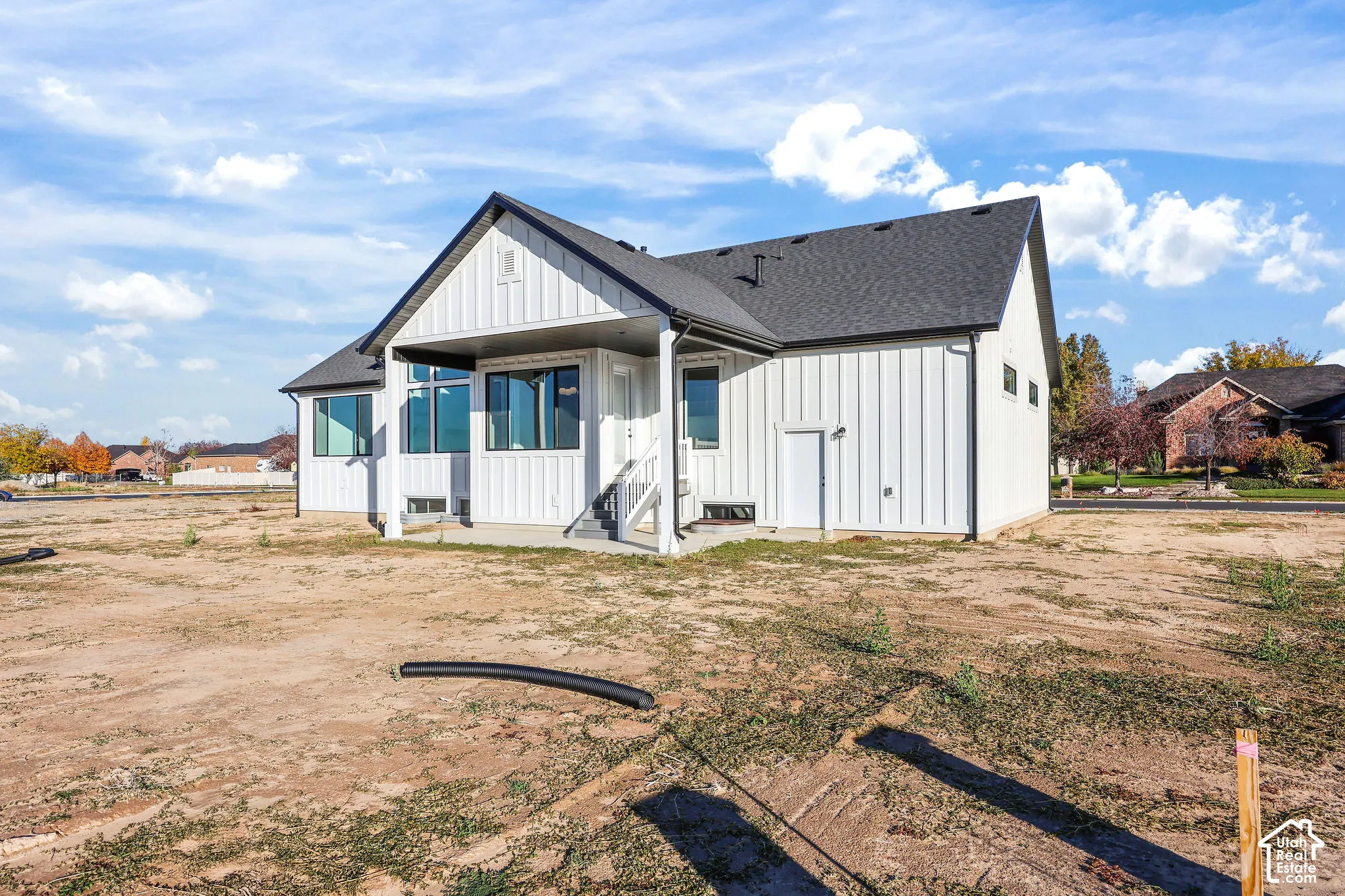 Modern farmhouse exterior featuring white vertical siding and a dark shingled roof
