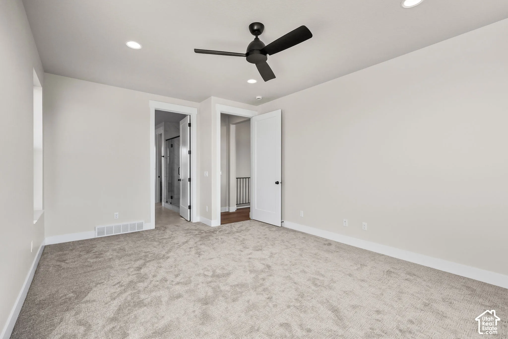 Spacious room featuring light-toned carpeting, recessed lighting, and a contemporary black ceiling fan